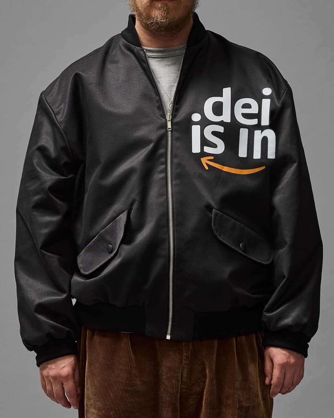 'DEI IN' Musta bomber -tyylinen takki kuvattuna mallin päällä.