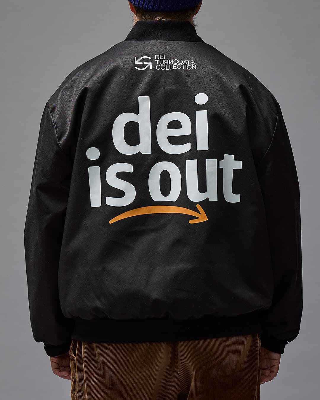 'DEI OUT' Musta bomber -tyylinen takki kuvattuna mallin päällä.